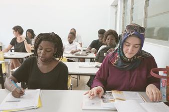 Etudiants en face d'un professeur en train de lever la main pour être interrogé