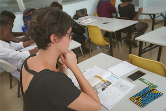 Etudiants en face d'un professeur en train de lever la main pour être interrogé